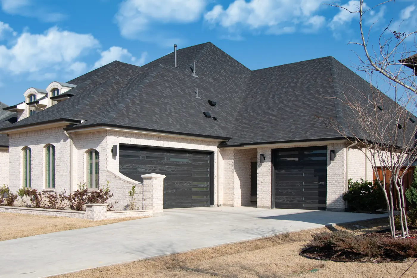 A white brick home with two black plank garage doors