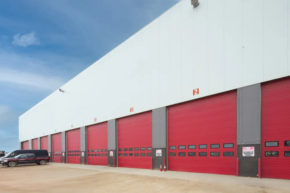 A row of red commercial doors on a white warehouse