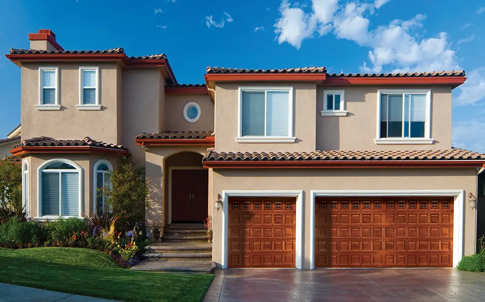 A two-story stucco home with wood-look garage doors