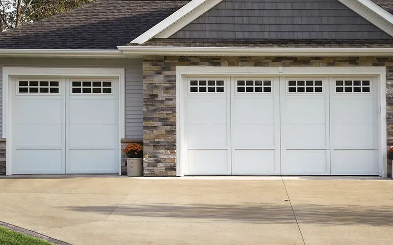 A home with white carriage-style garage doors and stone trim