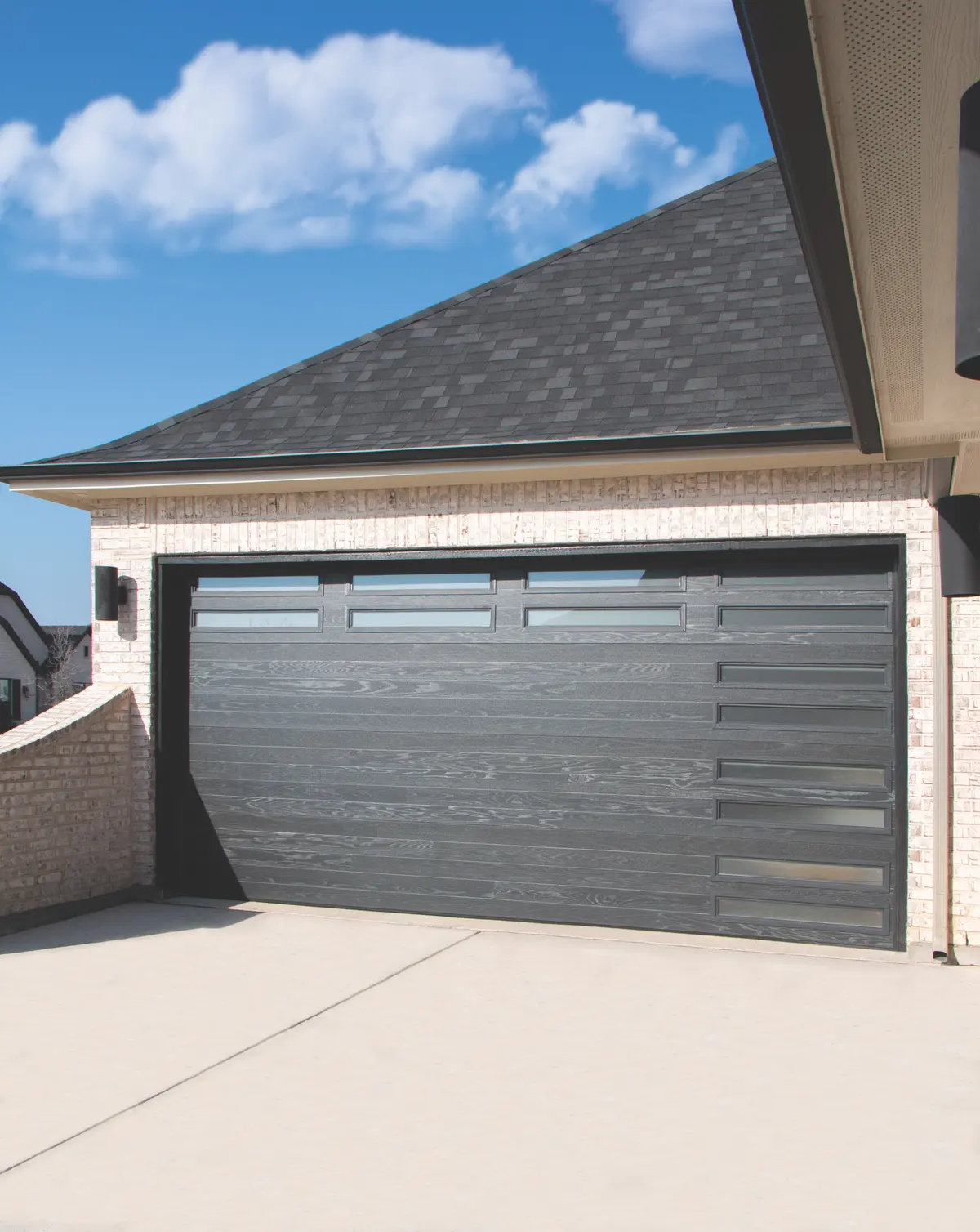 A black plank garage door on a gray brick home